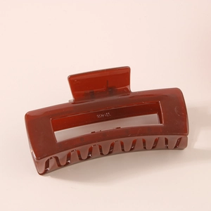 Detail view of the amber brown rectangular hair claw clip with glossy finish