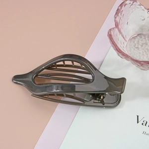 Détail d'une pince à cheveux gris foncé translucide avec design ajouré sur fond coloré