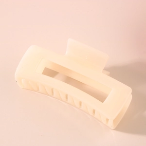 Close-up of cream rectangular hair claw clip with metal spring and smooth teeth
