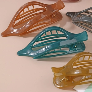 Détail de pinces à cheveux en résine translucide couleur ambre et vert au design creux