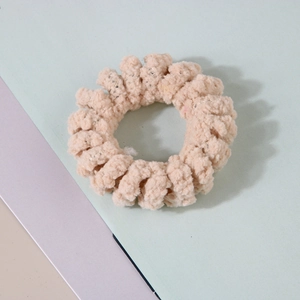 Gros plan détaillé d'un chouchou spirale en peluche beige à texture douce en laine