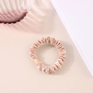 Dettaglio dell'elastico in velluto beige con trama a pieghe e fibbia in resina