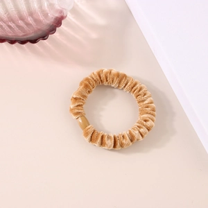 Dettaglio di un elastico per capelli in velluto con connettore in perla di resina marrone