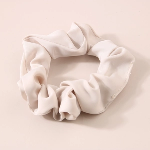 Detailed view of cream-colored milk silk scrunchie with soft satin texture and elegant pleats