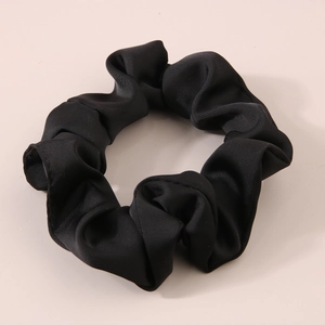 Close-up of black satin hair scrunchie with soft pleated texture and silk-like shine