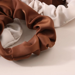 Detail of coffee and cream milk silk scrunchies with elegant pleated satin texture