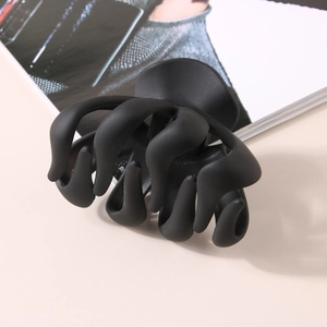 Détail de la pince à cheveux pieuvre noire mate de 8 cm avec texture givrée sur magazine