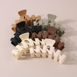 Macro detail of large matte hair claws in neutral earth tones with cross-tooth design