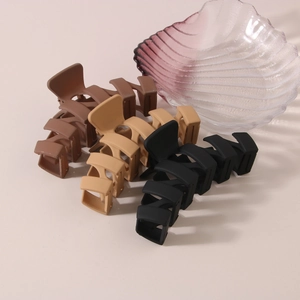 Detail of matte hair claws in black, dark brown, and khaki colors with cross design