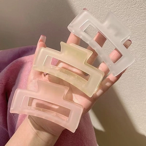 Detailed view of three matte large hair claw clips in pink, yellow, and white colors