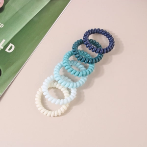 Five blue gradient spiral hair ties displayed on a beige background with green accents