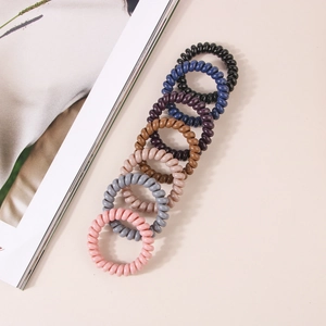 Flat lay of seven colorful spiral hair ties arranged on a minimalist background