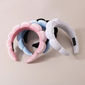 Detailed macro view of plush velvet spa headbands in pink, blue, white, and black colors