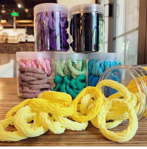 Macro shot of colorful gradient seamless hair ties with elastic wave texture in a clear jar