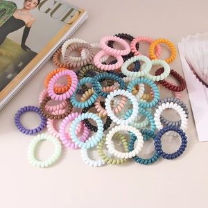 Macro shot of colorful spiral telephone wire hair ties stacked with a Vogue magazine prop
