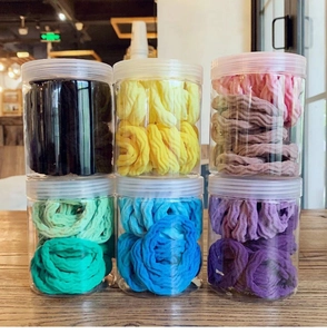 Macro shot of colorful thick seamless elastic hair ties stored in six transparent jars