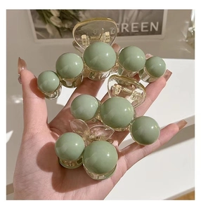 Detailed comparison of three sage green hair claws in different sizes held in a palm