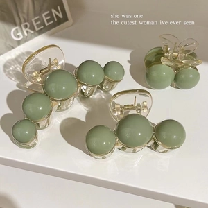 Three olive green hair claws in various sizes with pearl-like sphere designs