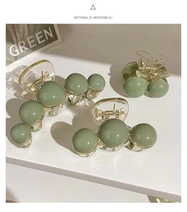 Detail view of avocado green acrylic hair claw clips with resin pearls and metal spring