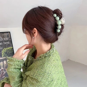 Elegant light green pearl hair claw clip for women styled on a low bun hairstyle