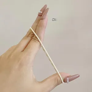 Close-up of cream elastic hair tie showing high stretchability and woven texture