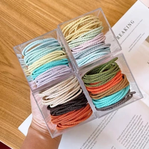 Macro detail of high-elasticity braided hair ties in colorful pastel and neutral tones