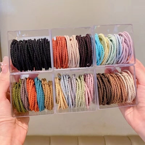 Elastic hair ties set with colorful braided design in a clear plastic storage organizer