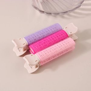 Tre fermagli per radici dei capelli in viola e rosa con rulli su uno sfondo beige