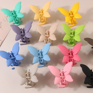 Flat lay of 12 matte butterfly hair claws in various vibrant colors on beige surface