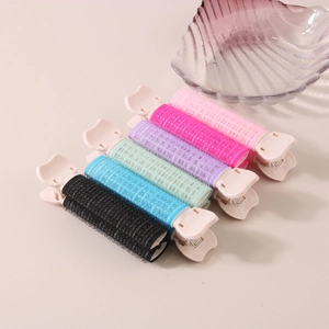 Dettaglio di clip colorate per radici per volume in rosa, blu, viola, verde e nero