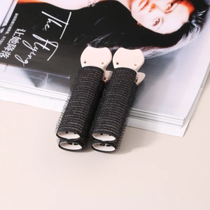 Dettaglio macro di bigodini in velcro neri con clip rosa per volume e styling dei capelli