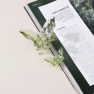 Détail de deux pinces à cheveux papillon vert clair translucides sur un magazine ouvert