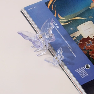 Détail des pinces à cheveux papillon violettes transparentes sur une revue
