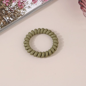 Gros plan d'un élastique spirale vert olive mat sur un fond rose clair minimaliste