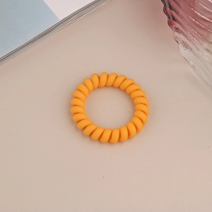 Gros plan d'un élastique spirale orange mat sur un fond de texture minimaliste