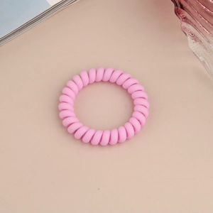 Vue de dessus d'un élastique spirale rose mat sur un fond beige minimaliste épuré
