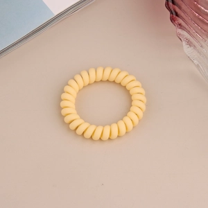 Vue détaillée d'un élastique spirale jaune mat sur un fond décoratif et esthétique moderne
