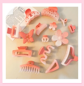Flat lay of 14 gradient pink matte hair claws in various butterfly and floral shapes