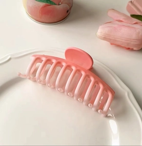 Detail of large matte gradient pink shark hair claw clip placed on a white decorative plate