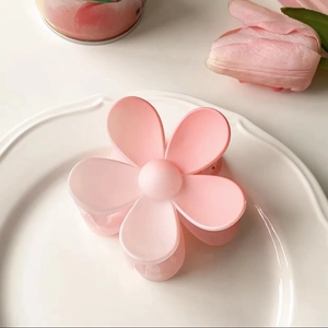 Close-up of a gradient pink cherry blossom hair claw clip on a white decorative tray