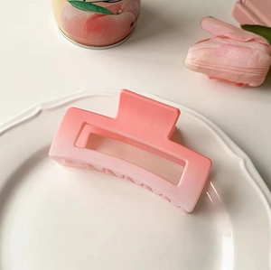 Macro shot of matte gradient pink hair claw clip on ceramic plate with tulip decor