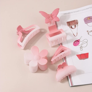 Detail view of matte gradient pink and white hair claws in diverse shapes on a neutral background