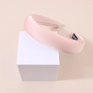 Detail of pink satin padded headband with 'HAND MADE' label on smooth fabric