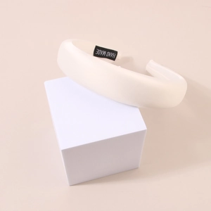 Detail of white satin sponge headband showing the handmade label on interior