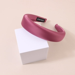 Detailed close-up of a padded berry pink satin headband with a handmade inner label