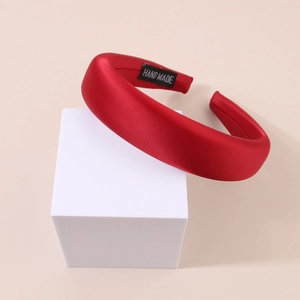 Detail of red satin padded headband featuring a handmade label on the smooth inner lining
