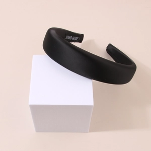Detail of wide black satin headband with handmade label on anti-slip inner lining