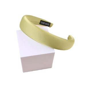 Padded satin headband in pistachio green featuring a handmade fabric label on the inner side