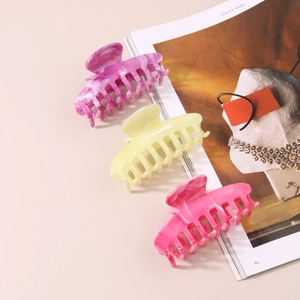 Detailed view of large marble texture hair claws in yellow, purple and rose pink colors