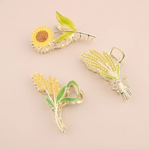 Vue détaillée de trois pinces à cheveux en alliage doré avec motifs tournesol et épi de blé